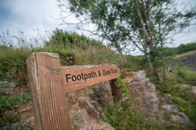 Wooden signpost with footpath and geo-trails written on it pointing towards a pathway.