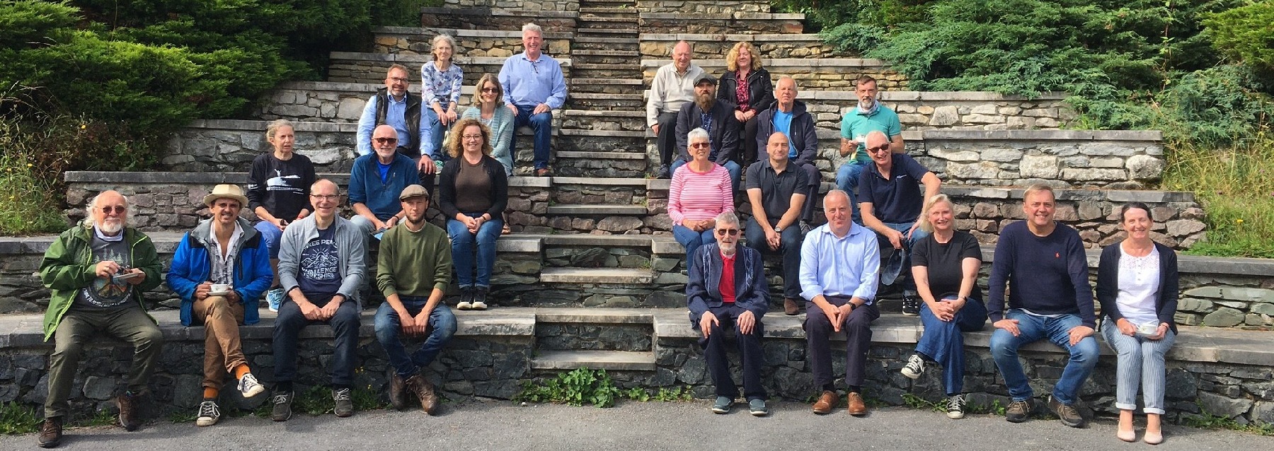Group of people sat on wide steps at different levels smiling for the camera.